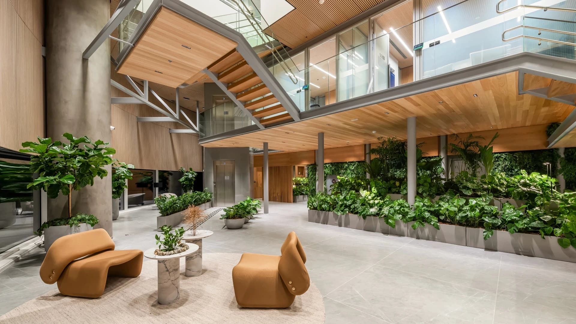 Corporate office with high ceilings, wood, plants and armchairs